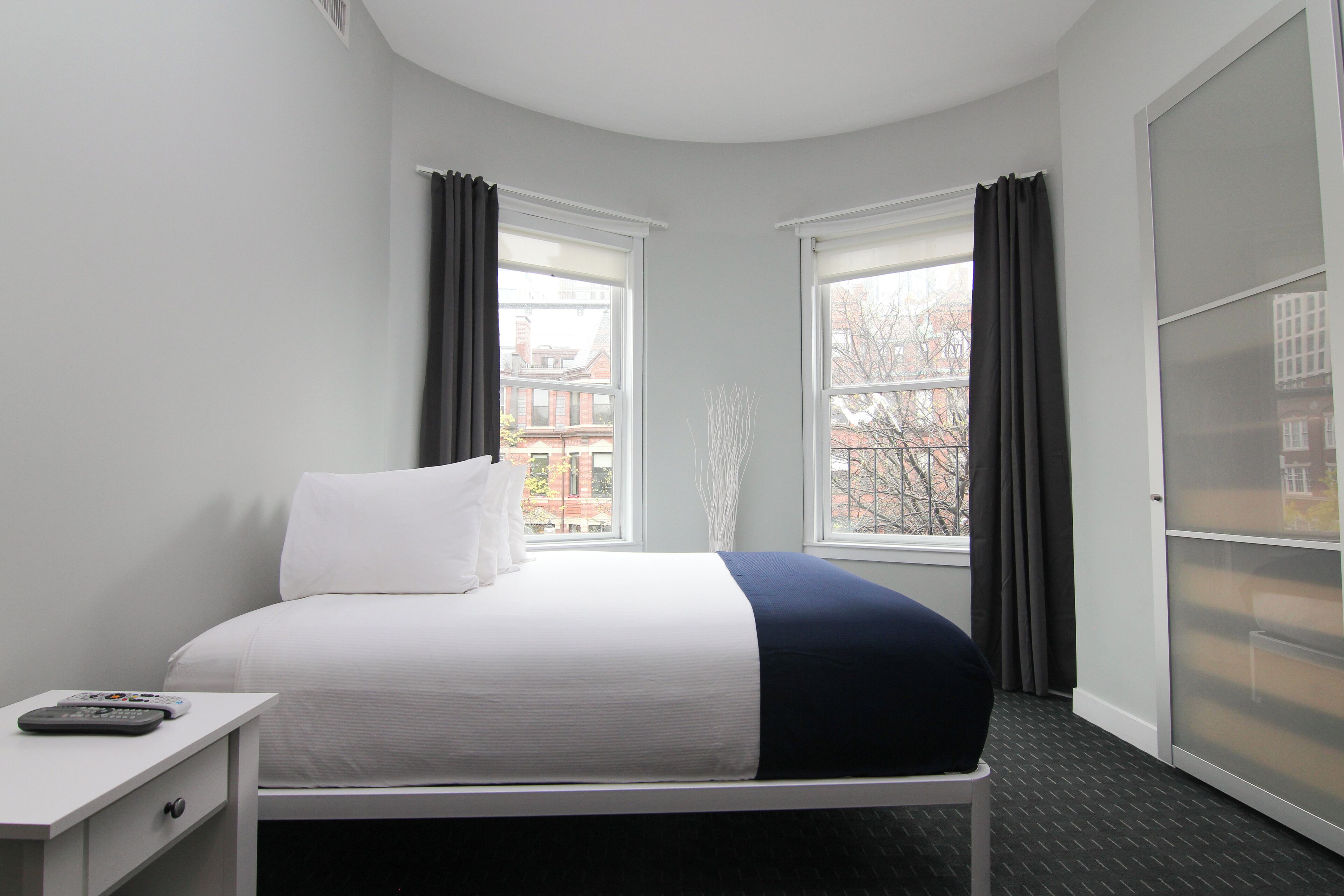 Una camera d'albergo con un letto, un comodino e una finestra con tende.