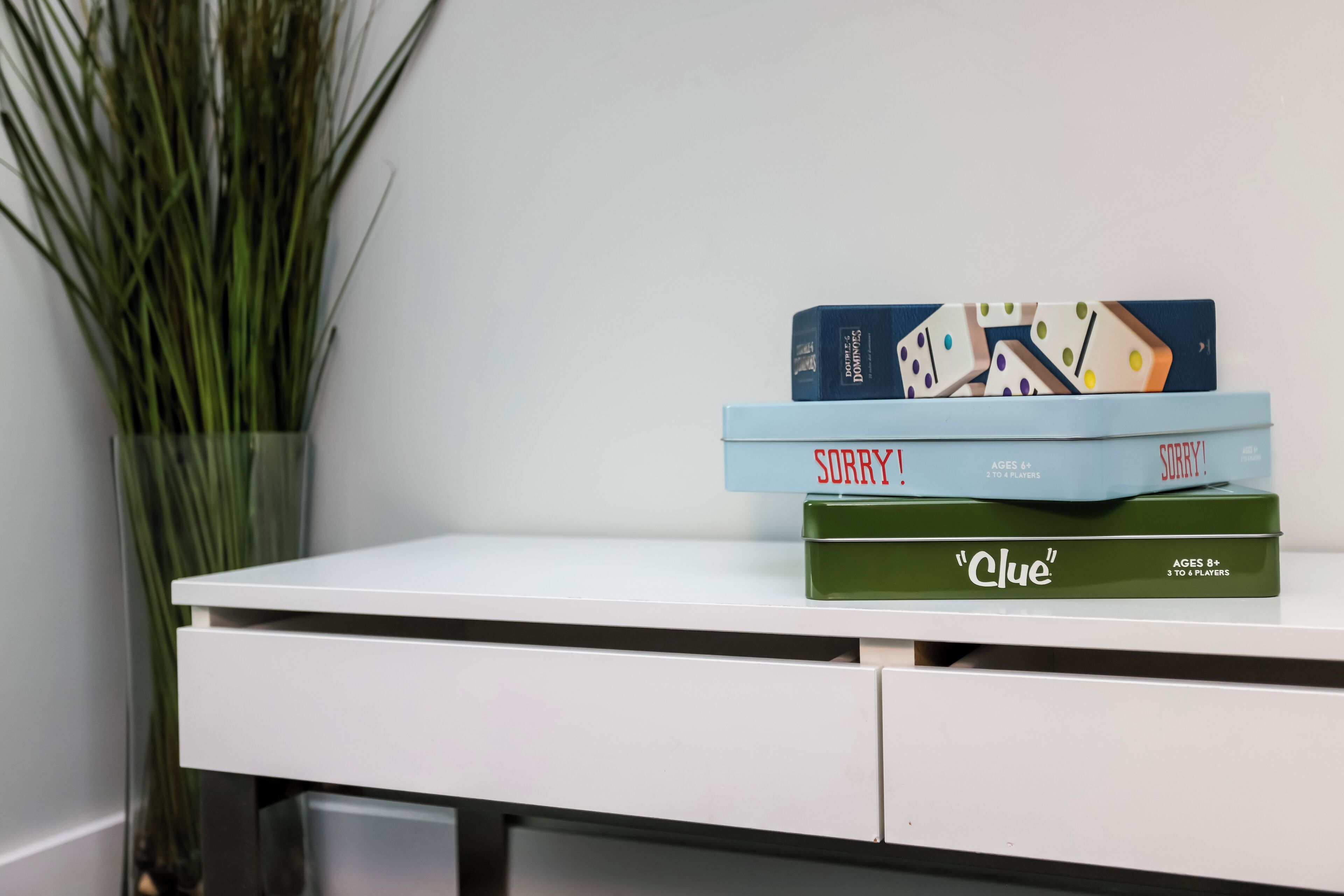 A white desk with three board games stacked on top.