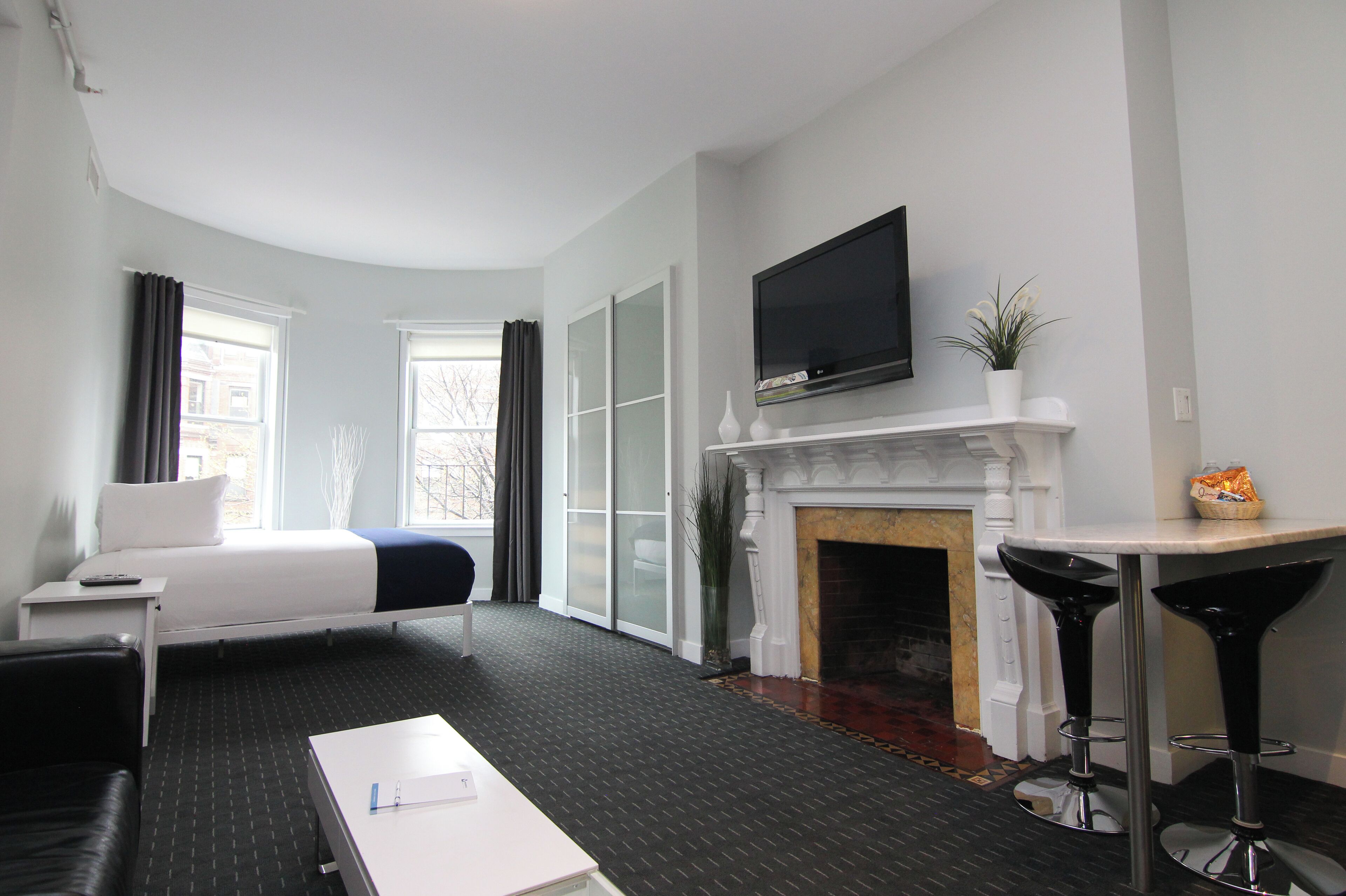 Een hotelkamer met een bed, een televisie, een open haard en twee barkrukken.