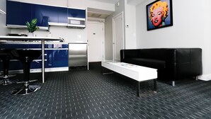 A modern kitchen with blue cabinets, a white countertop, and a black sofa.