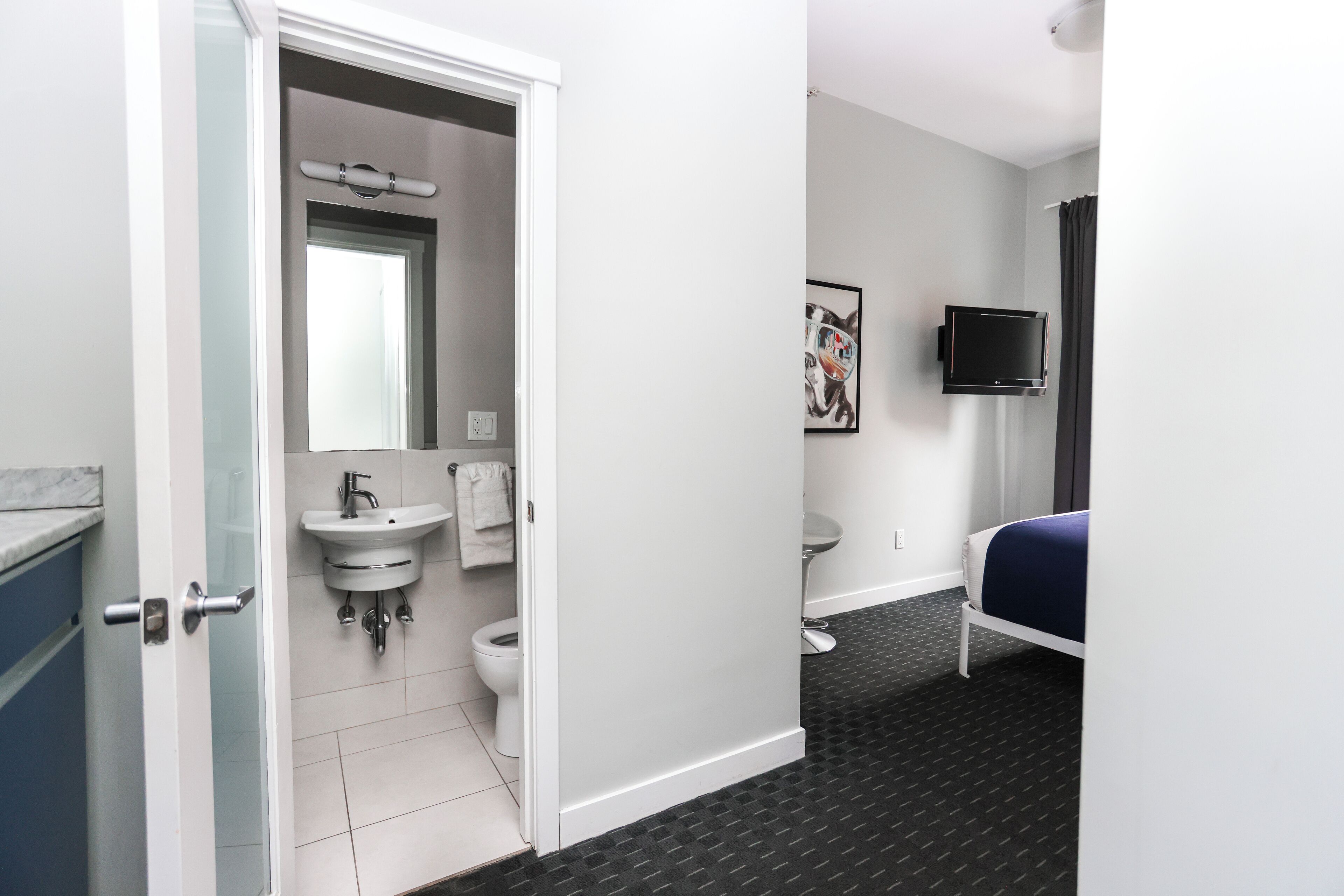 Une chambre d’hôtel avec une salle de bain, un lit, une télévision et un tableau au mur.