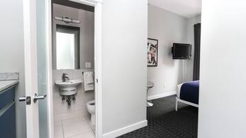 Une chambre d’hôtel avec une salle de bain, un lit, une télévision et un tableau au mur.