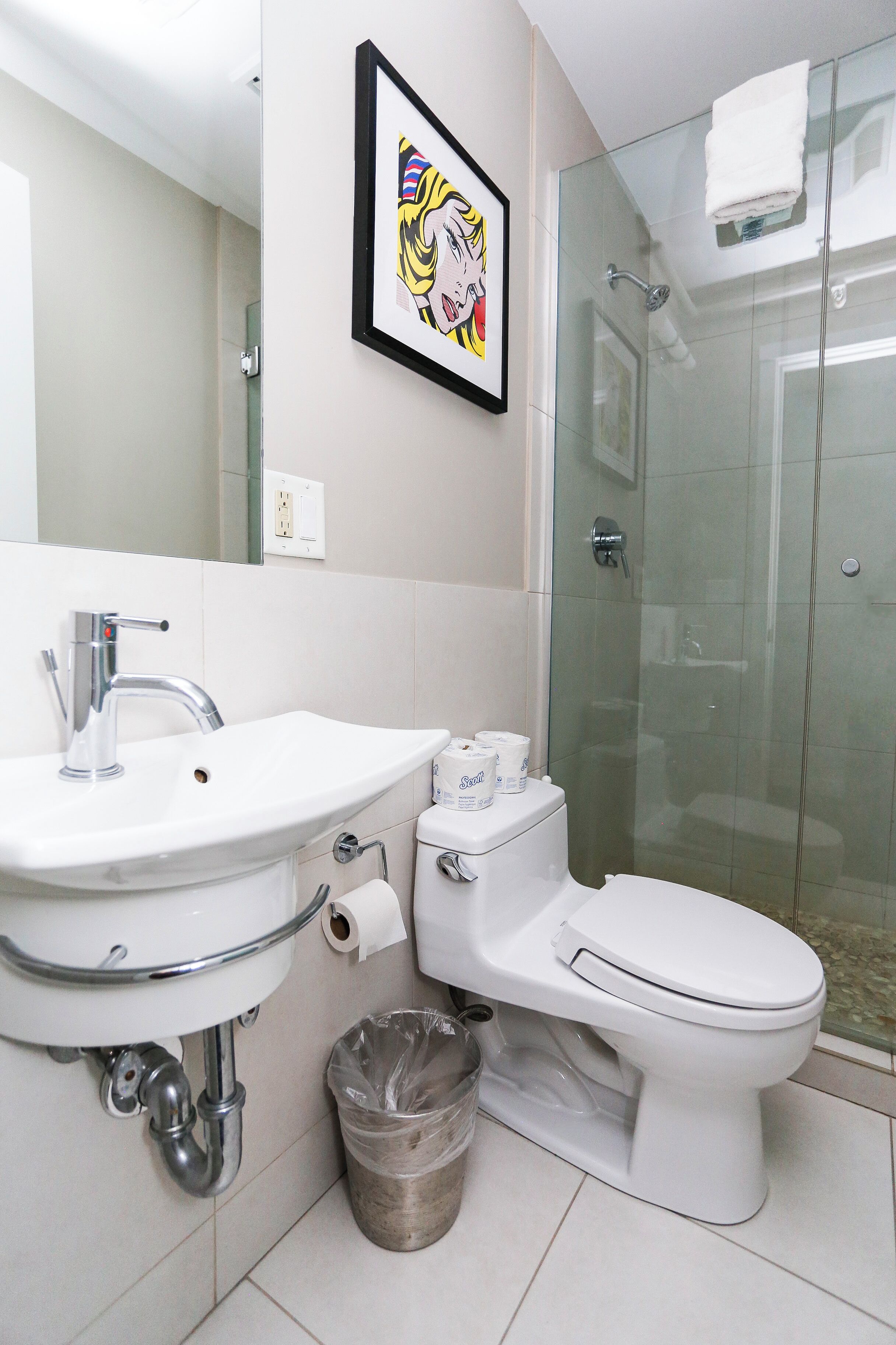 Une salle de bain moderne avec un lavabo blanc, des toilettes et une douche à parois de verre.