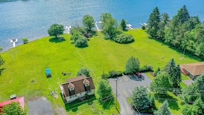 An aerial view of a property with a large grassy area, a small building, and a dock extending into a body of water. - Villages of the Wisp 25 Liftside (McHenry)