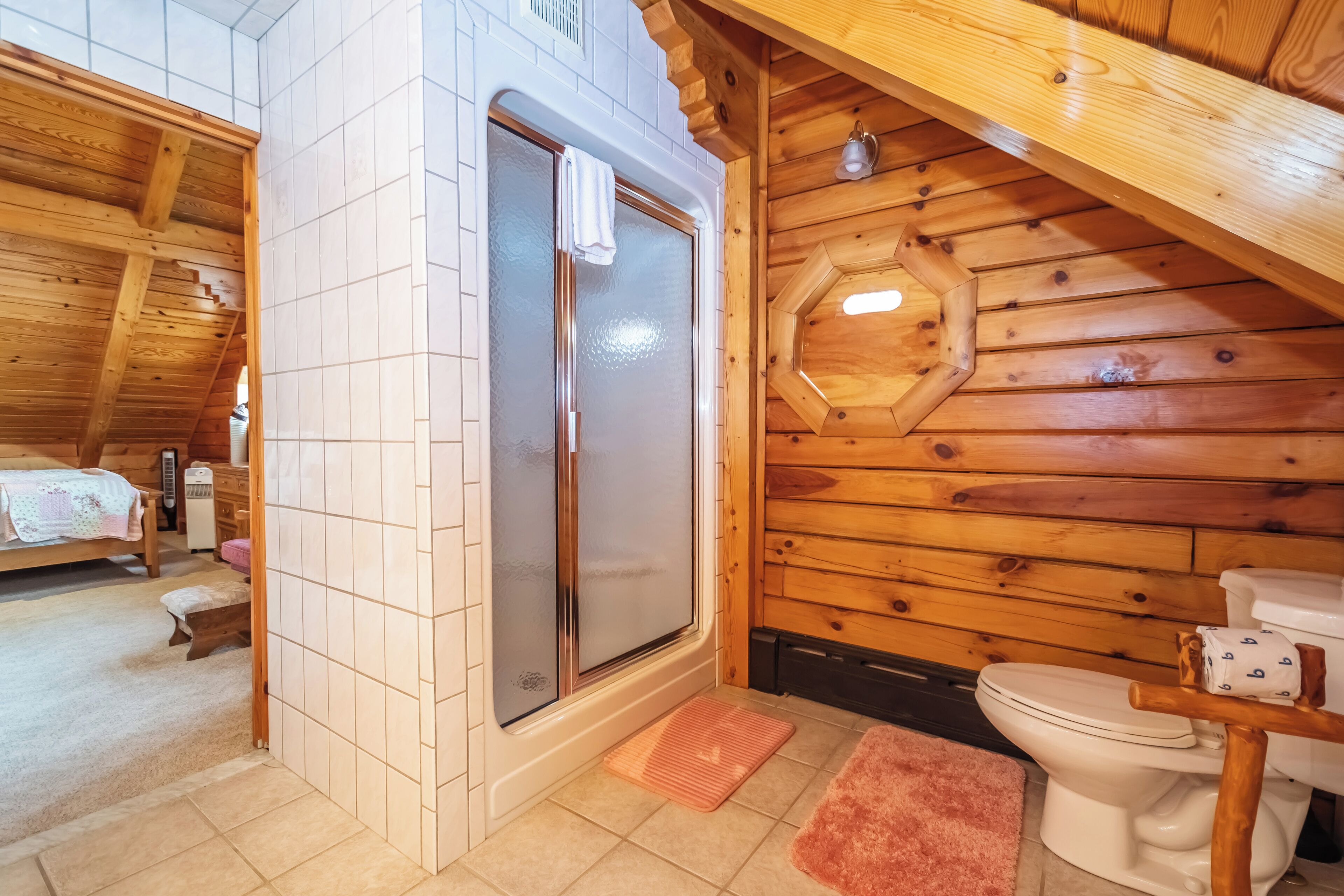 Ein Badezimmer einer Holzhütte mit Dusche, Toilette und einer kleinen Bank.