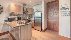 A modern kitchen with granite countertops, stainless steel appliances, and wooden cabinets. - 1BR 4 Guests Golf View Course Casa de Campo (La Romana)
