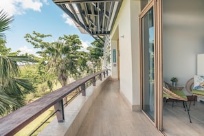 Un balcon avec une balustrade en bois, une porte vitrée et des chaises en osier.