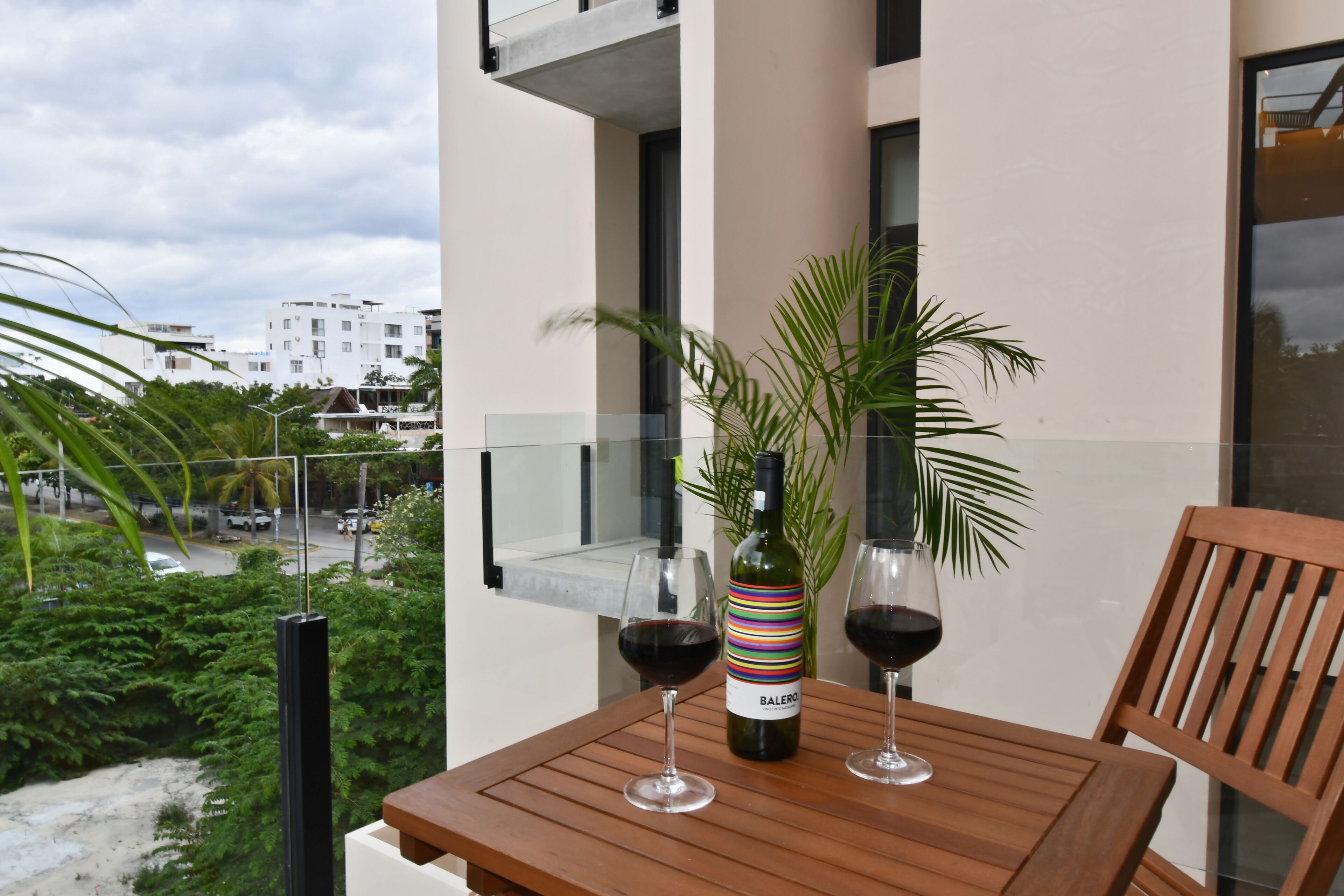A balcony with a table, two wine glasses, and a bottle of wine.