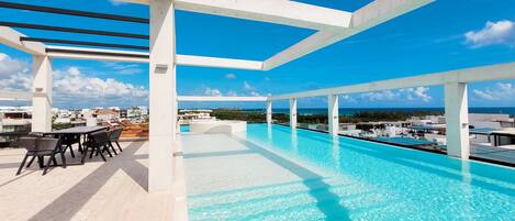 A rooftop infinity pool with a clear view of the ocean and cityscape.