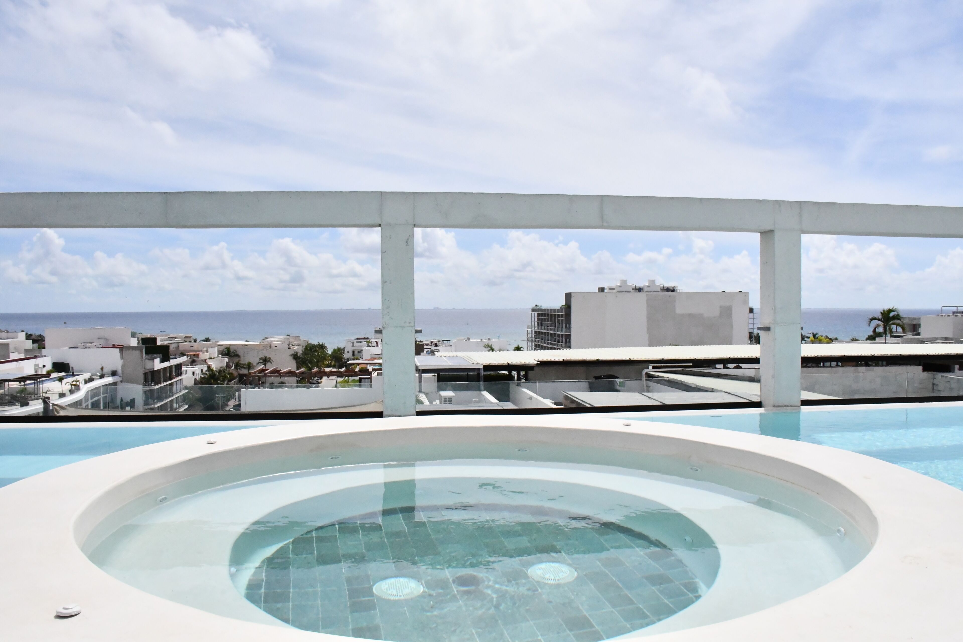 A rooftop infinity pool with a clear view of the city skyline and the ocean.