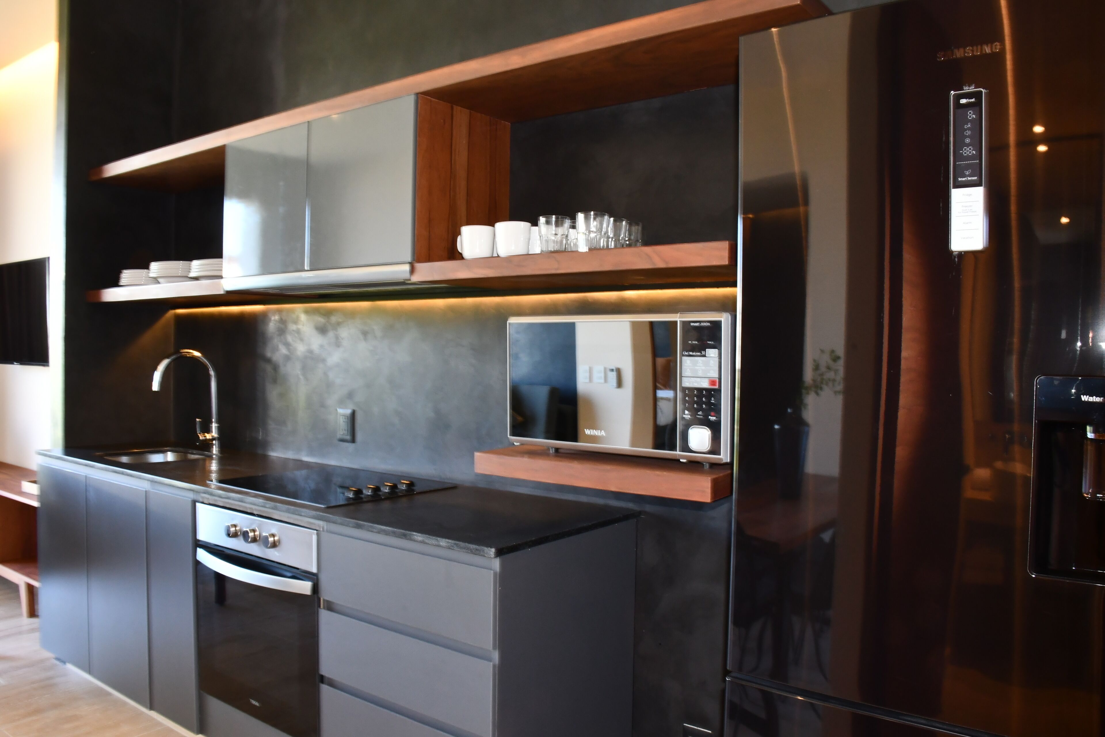 A modern kitchen with a built-in oven, microwave, and refrigerator.