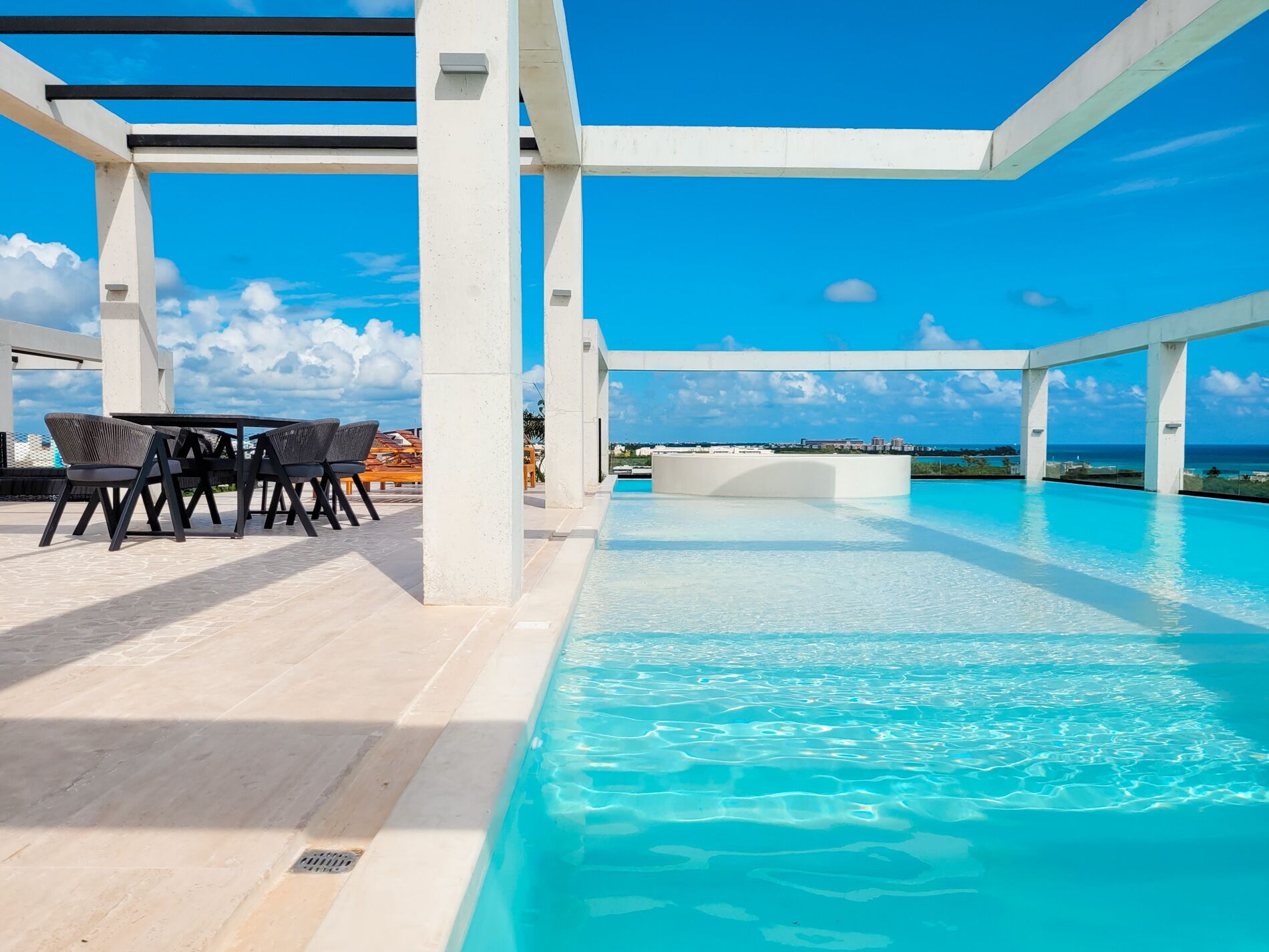 An infinity pool with a clear blue sky and a view of the ocean.