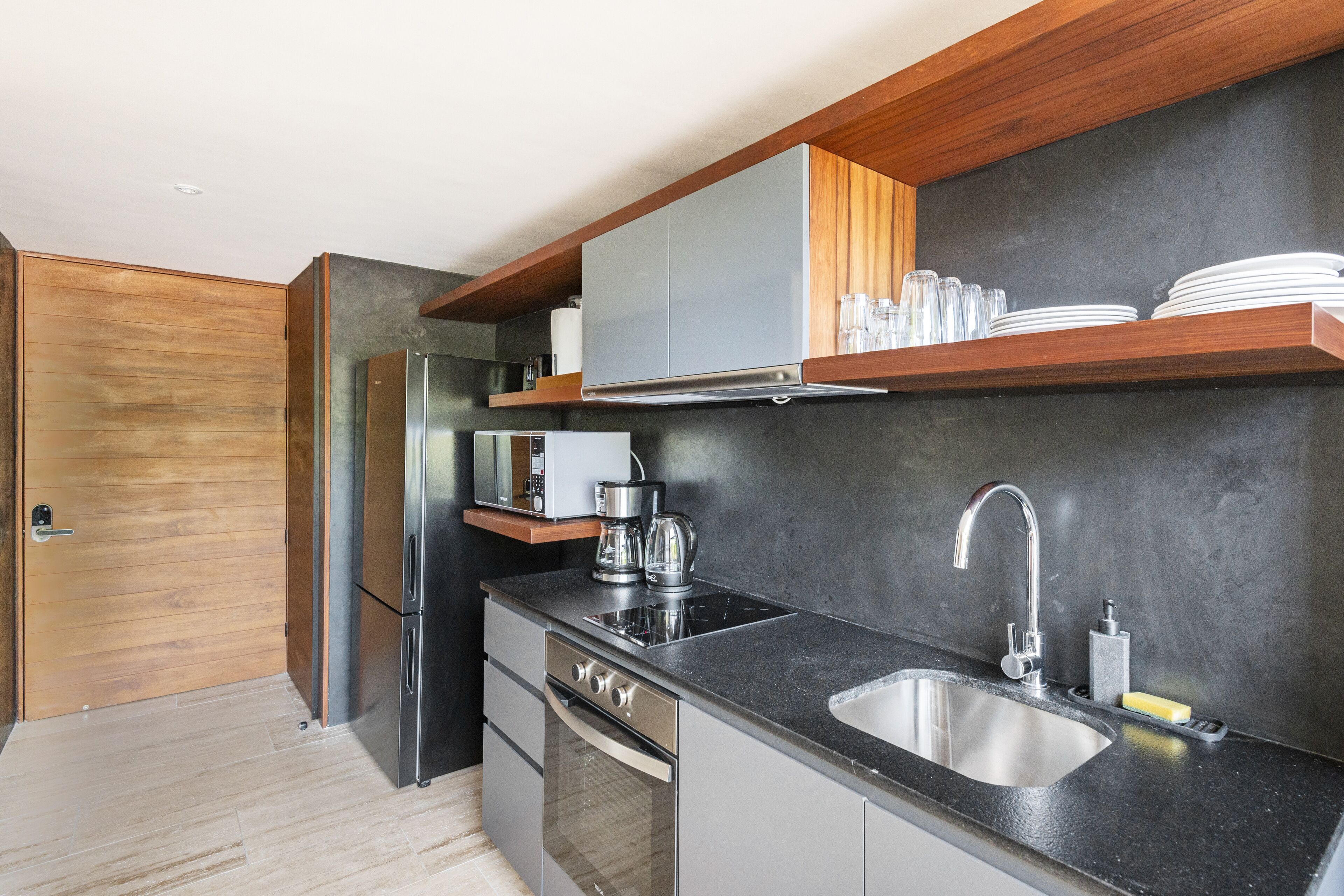 A modern kitchen with stainless steel appliances, a black countertop, and wooden accents.