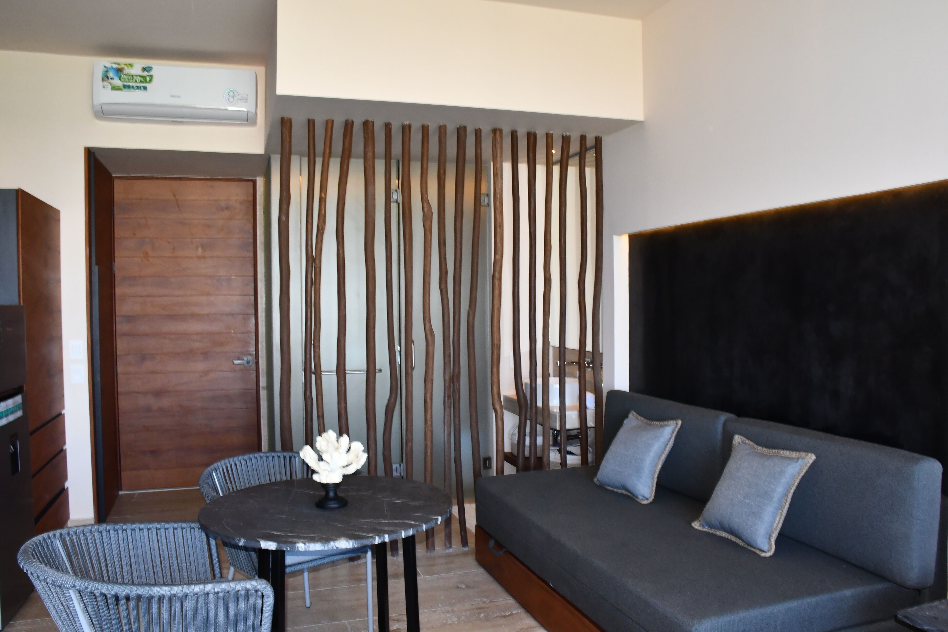 A modern room with a sofa, a dining table, and a decorative wall panel.