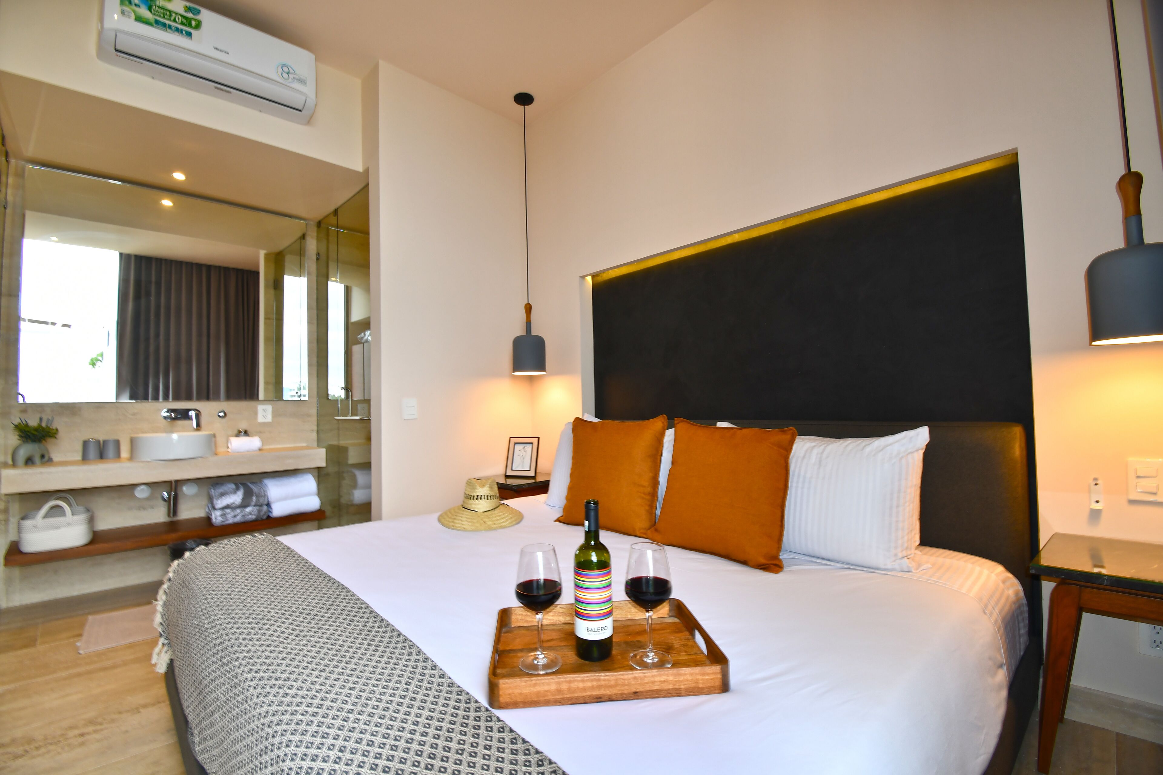 Ein Hotelzimmer mit Bett, Nachttisch, Waschtisch und einem Badezimmer mit Waschbecken und Spiegel.