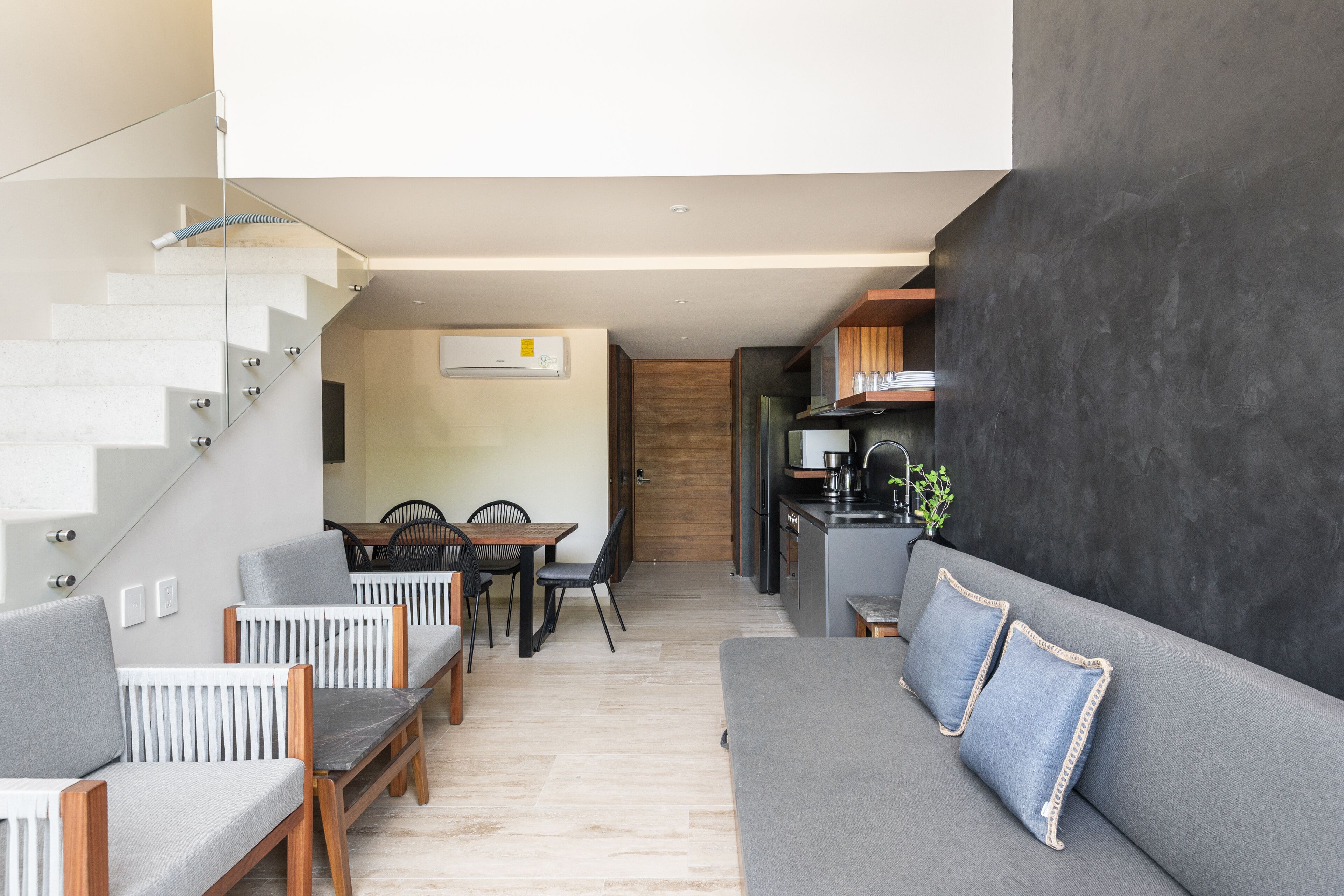 A modern interior with a staircase, dining area, and kitchen.