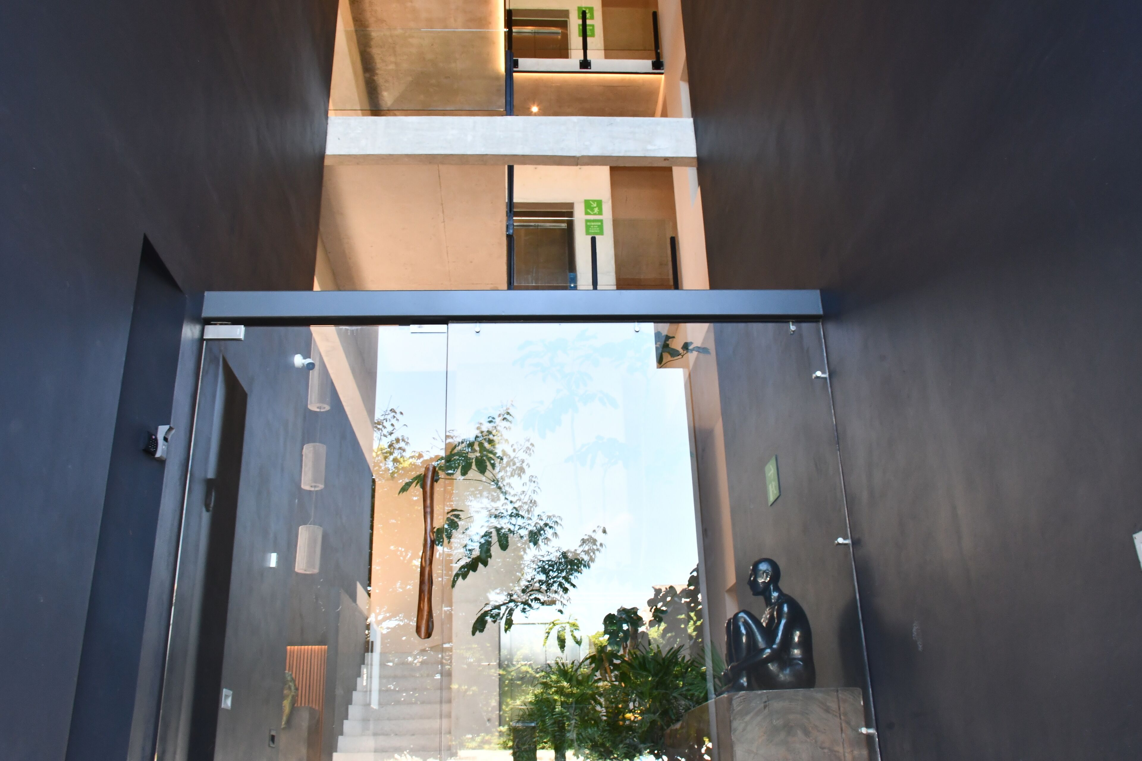 A modern building entrance with a glass door, a staircase, and a statue.