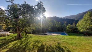 A backyard with a swimming pool, surrounded by lush greenery and a mountainous backdrop. - Rural house, ideal for families in the middle of nature. (Júzcar)