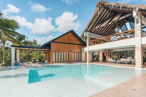 Un resort con piscina, edificio de madera y estructura de techo de paja.