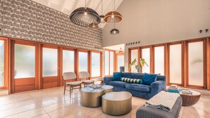Ein geräumiges Wohnzimmer mit einem blauen Sofa, runden Couchtischen und einem großen Fenster mit Milchglasfenstern.