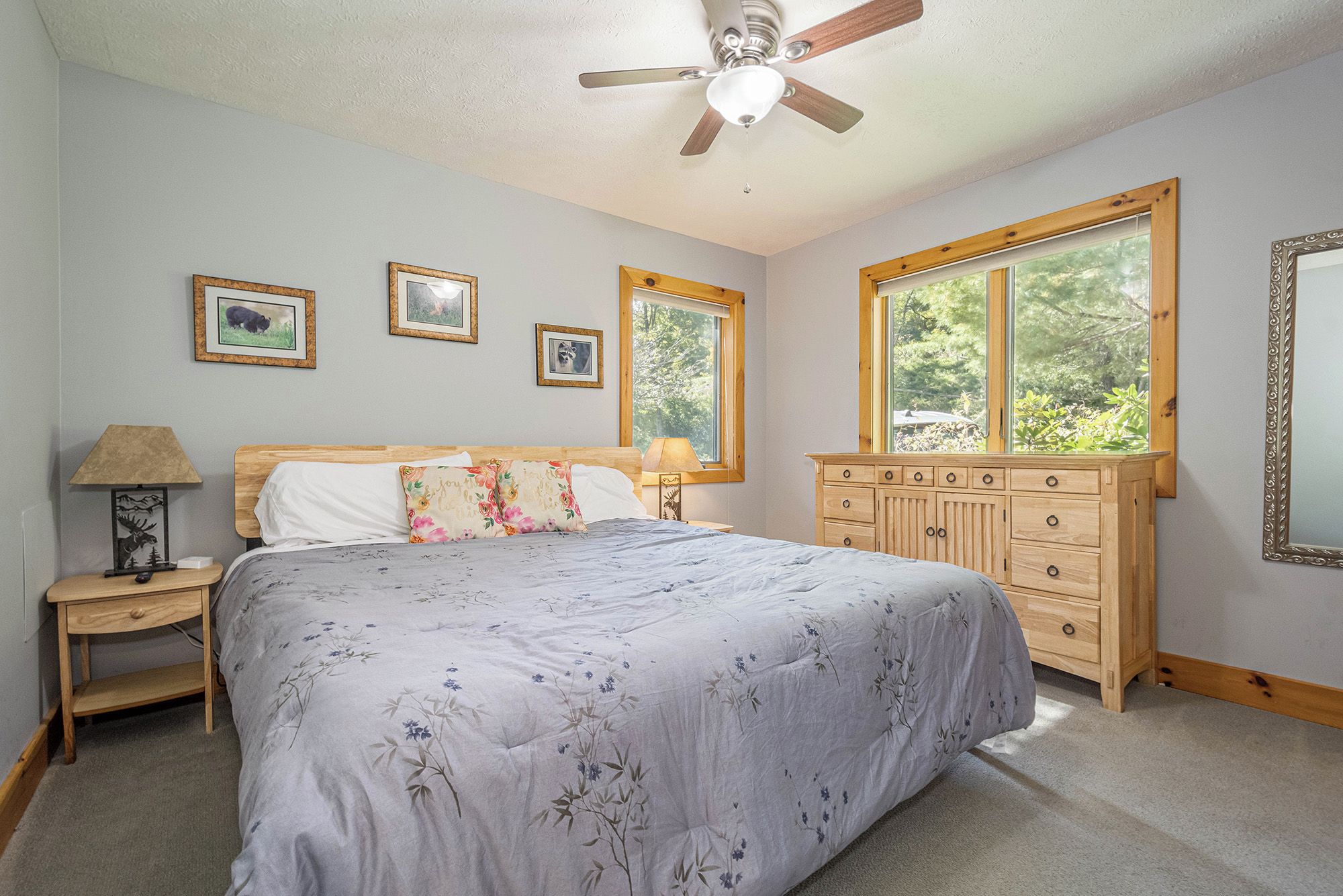 A bedroom with a bed, nightstands, a dresser, and framed pictures on the wall.