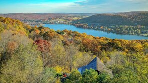A panoramic view of a lakeside town with autumn foliage, a prominent blue-roofed building, and a river in the background.
