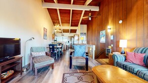 A cozy living room with a television, seating, a dining area, and a kitchen.