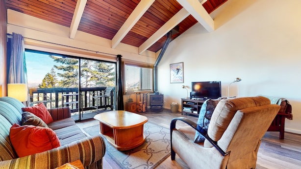 A spacious living room with a large window, a fireplace, a television, and a cozy seating area.