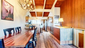 A modern kitchen with wooden cabinets, a stainless steel refrigerator, and a wooden dining table with chairs.