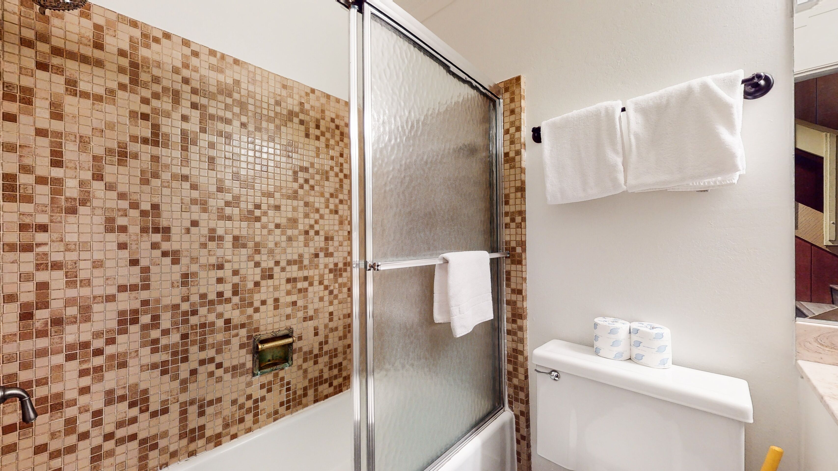 A bathroom with a shower, toilet, and towel rack.