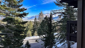 A mountain view from a cabin with a wooden deck and a clear blue sky.
