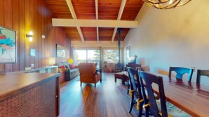 A spacious room with a wooden ceiling, a reception desk, a sofa, and a dining area with chairs.