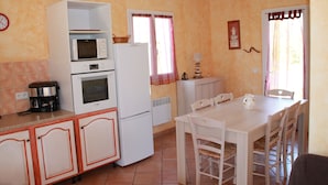 A kitchen with a microwave, oven, and refrigerator. There is a dining table with chairs and a coffee maker. - Semi-detached mini villa for 6 people in a small, quiet, natural family residence (San-Gavino di Carbini)