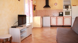A compact kitchen with a microwave, oven, and sink. There's a dining area with a sofa and a small table. - Semi-detached mini villa for 6 people in a small, quiet, natural family residence (San-Gavino di Carbini)