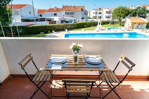 A terrace with a table set for two, overlooking a swimming pool and residential buildings. - Silchoro - Charming, renovated studio with pool and AC (Albufeira)