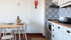 Une cuisine compacte avec des meubles blancs, un pare-feu en carreaux et un coin repas avec une table dressée pour deux personnes.