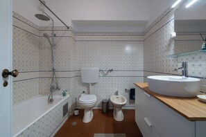 A bathroom with a bathtub, toilet, bidet, and sink. - Silchoro - Charming, renovated studio with pool and AC (Albufeira)