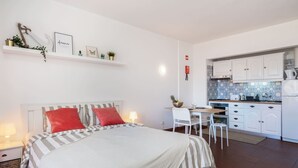 Une chambre comprenant un lit, des tables de chevet, un bureau et un coin cuisine.