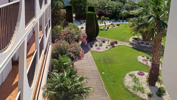 Ein modernes Gebäude mit einzigartigem architektonischen Design, mit Balkonen und einem gepflegten Garten mit unterschiedlichen Pflanzen und einem Weg.