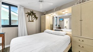 Ein Schlafzimmer mit Bett, Kleiderschrank, Spiegel und einem Fenster mit Vorhängen.