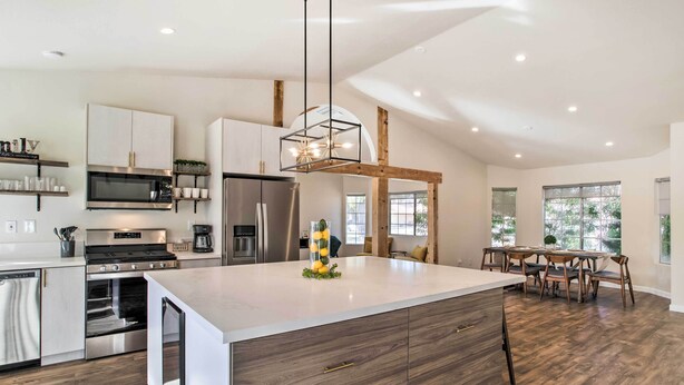 Una cocina moderna con una isla central, electrodomésticos integrados y una zona de comedor con sillas de madera.