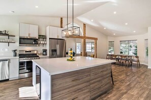 Una cucina moderna con isola centrale, elettrodomestici integrati e zona pranzo con sedie in legno.