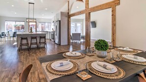 Un comedor moderno con una mesa de madera oscura dispuesta para cuatro personas, rodeada de individuales tejidos y platos blancos.