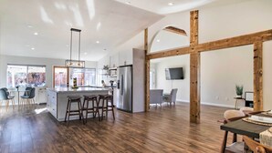 Una cocina amplia con una isla central, vigas de madera y un ventanal grande.