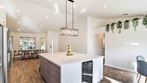 Una cocina moderna con una isla central, piso de madera y una lámpara colgante.