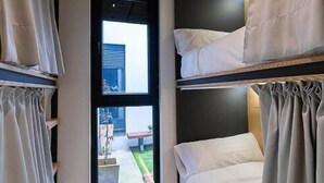 A compact room with bunk beds, a window with a view of the outside, and a small table. - dpaso hostel (Chantada)