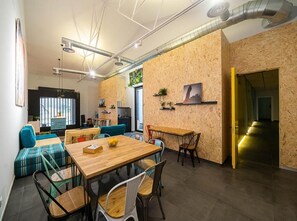 A modern interior with a wooden dining table, chairs, and a seating area with cushions. - dpaso hostel (Chantada)