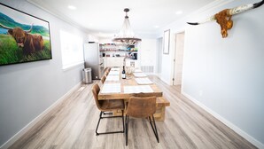 A dining area with a wooden table set for six, a chandelier, and a mounted animal skull on the wall. - The Farmstead- Pool, Hot Tub, Firepit and Farm Fresh Eggs/Animals in Walla Walla (Walla Walla)