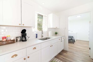 Une cuisine moderne avec des meubles blancs, un coin café et une fenêtre offrant une belle vue.