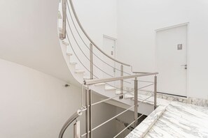 A curved staircase with metal railings and marble flooring.
